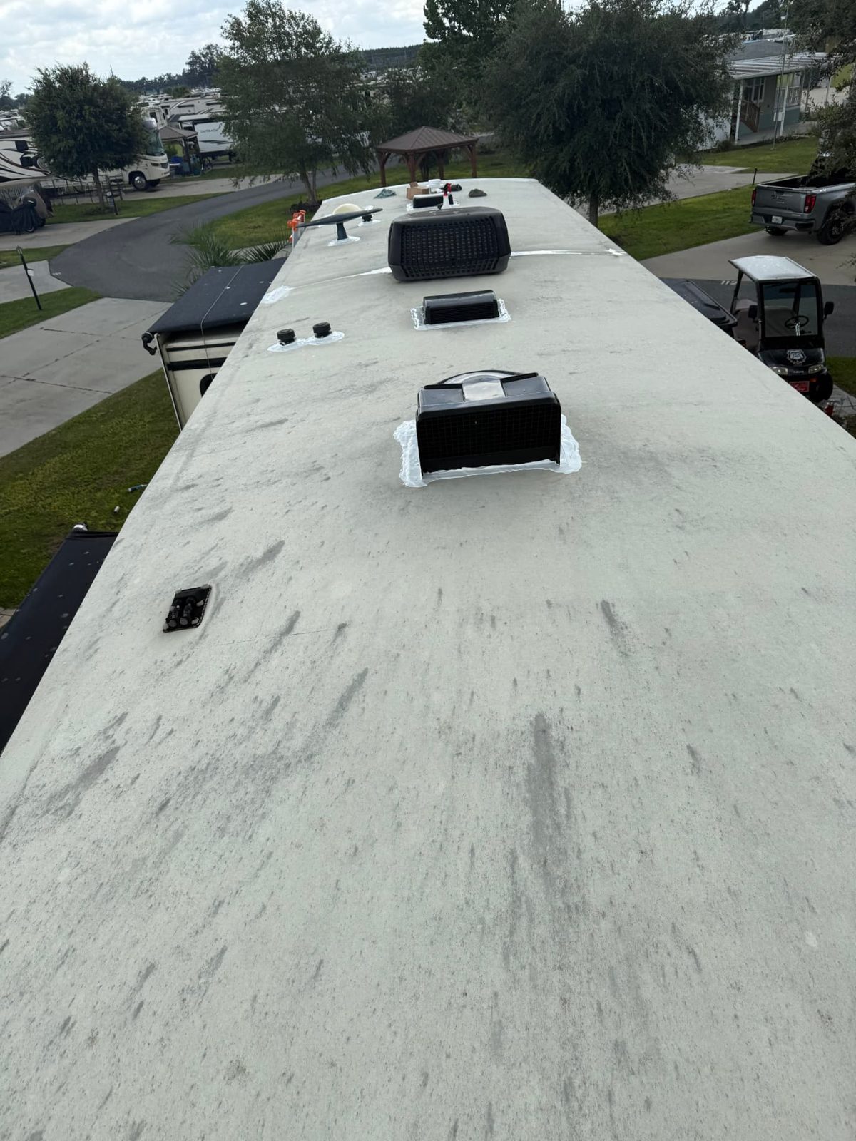 RV roof at a campground with air conditioner and vents freshly sealed